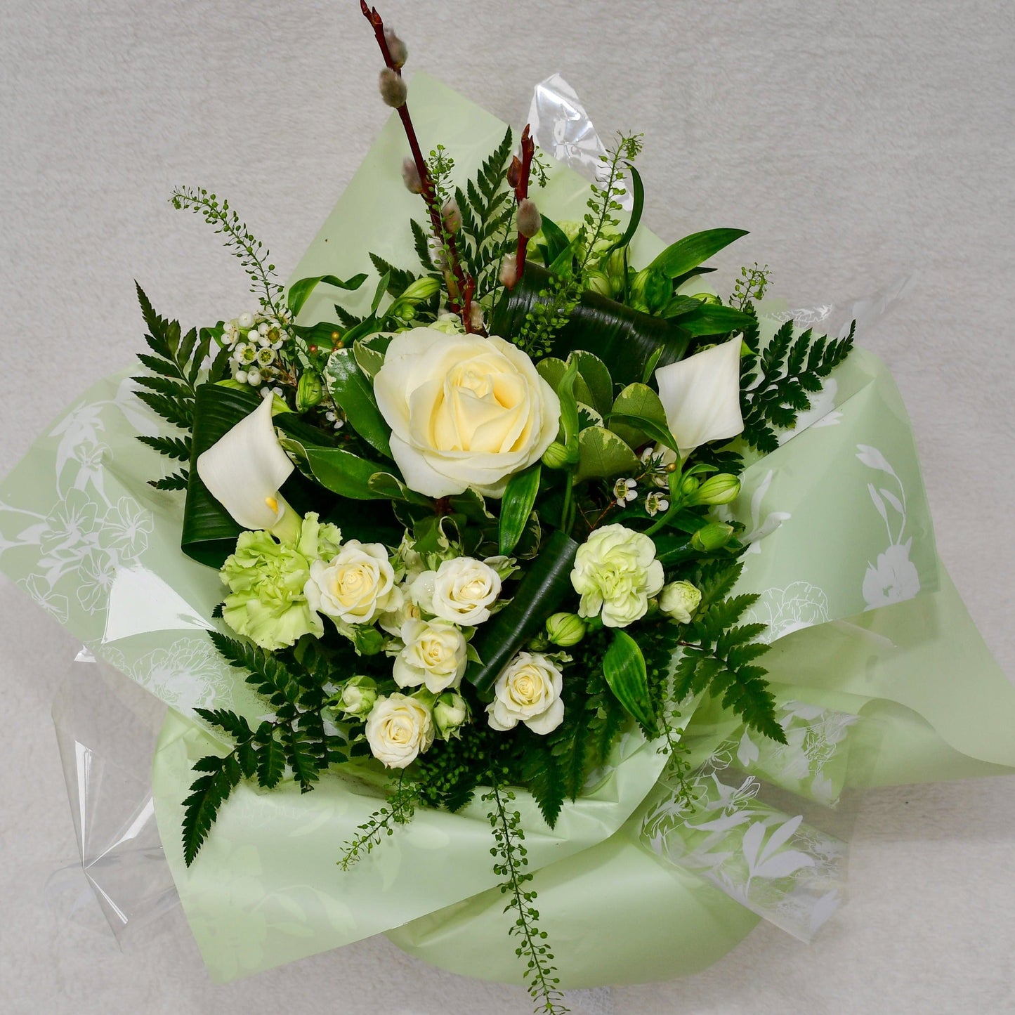 Hand-tied, gift wrapped bouquet including a selection of green and white flowers with complimentary foliage