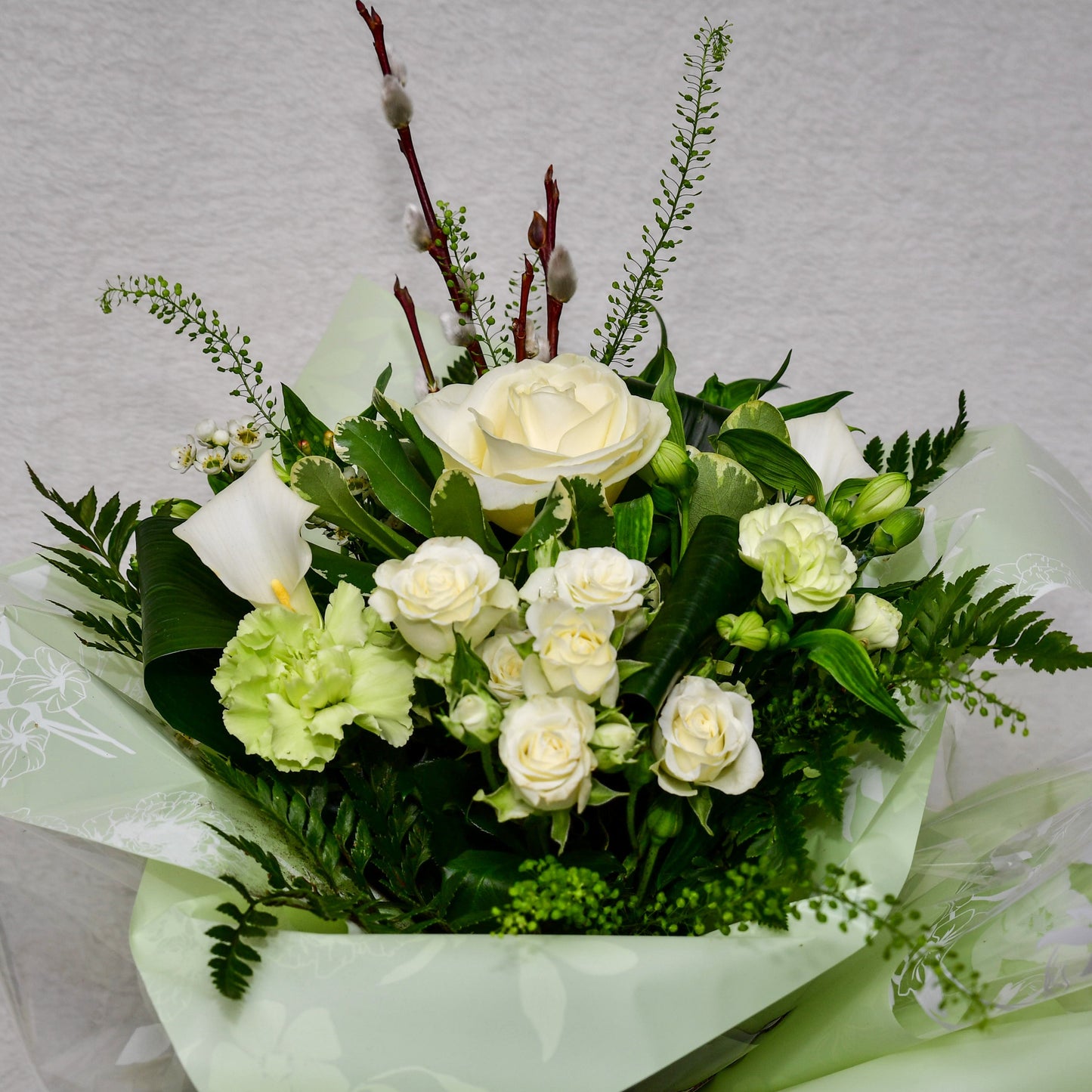 Hand-tied, gift wrapped bouquet including a selection of green and white flowers with complimentary foliage