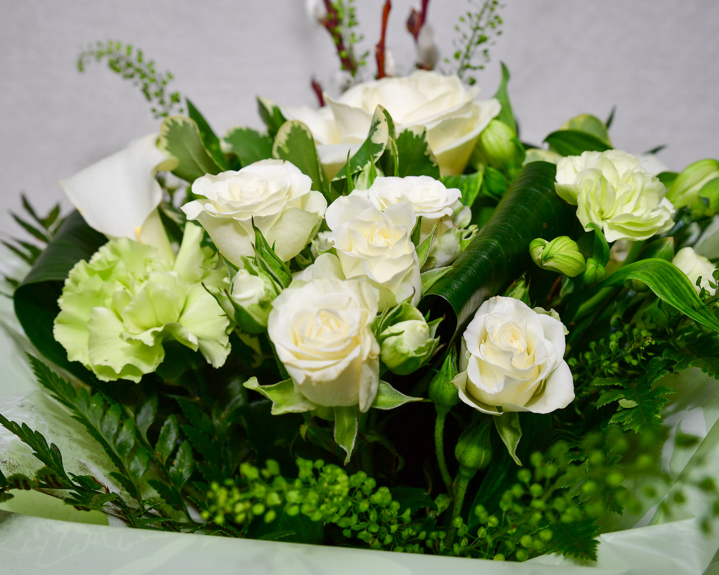 Hand-tied, gift wrapped bouquet including a selection of green and white flowers with complimentary foliage