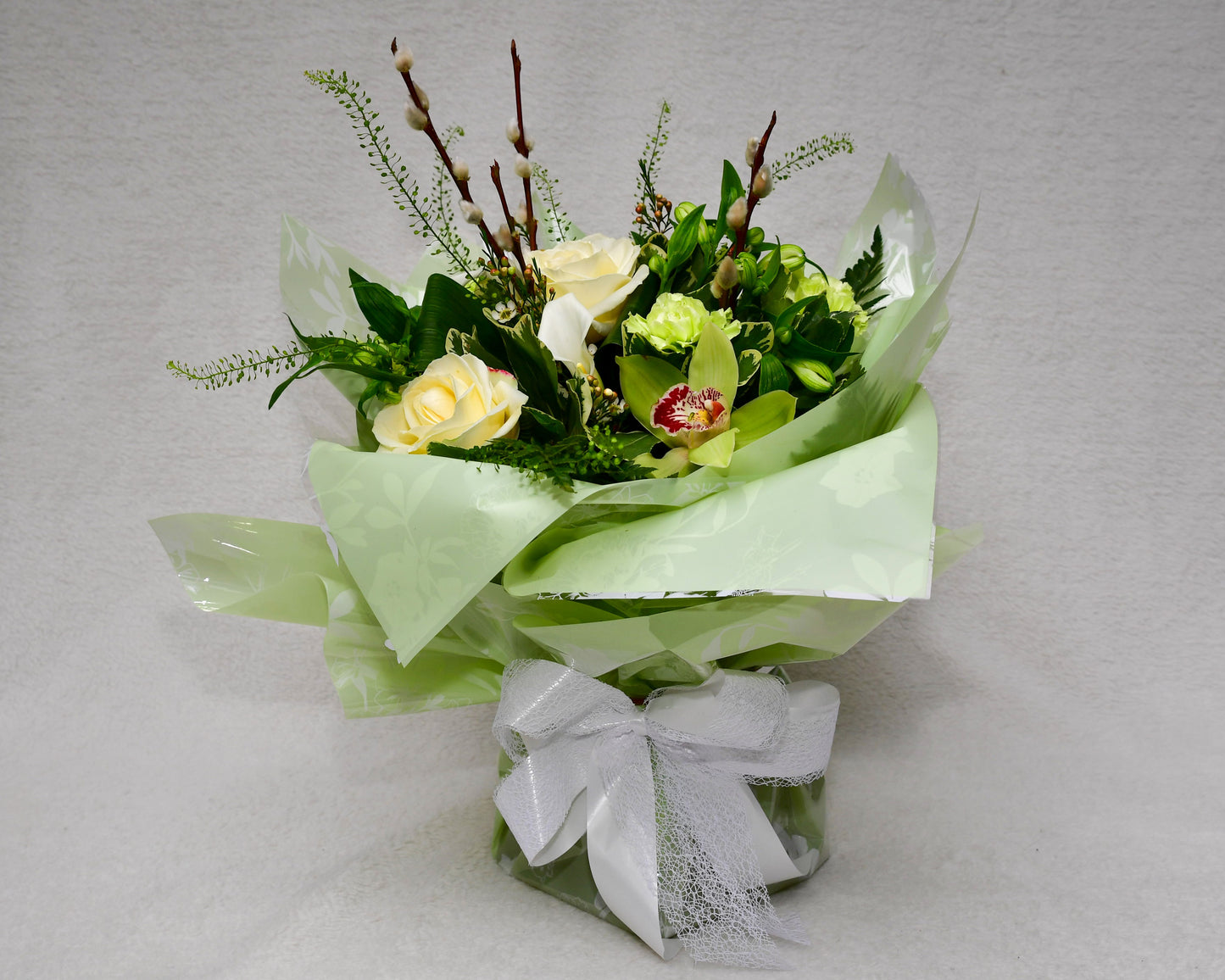 Hand-tied, gift wrapped bouquet including a selection of green and white flowers with complimentary foliage