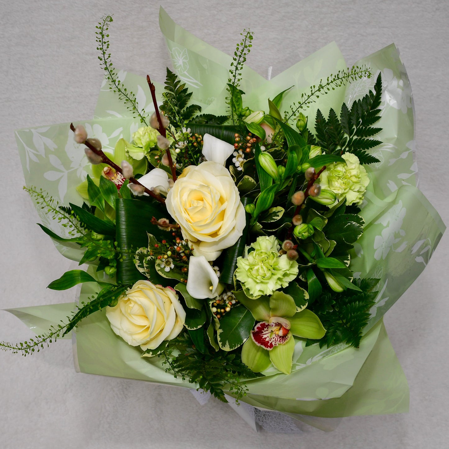 Hand-tied, gift wrapped bouquet including a selection of green and white flowers with complimentary foliage