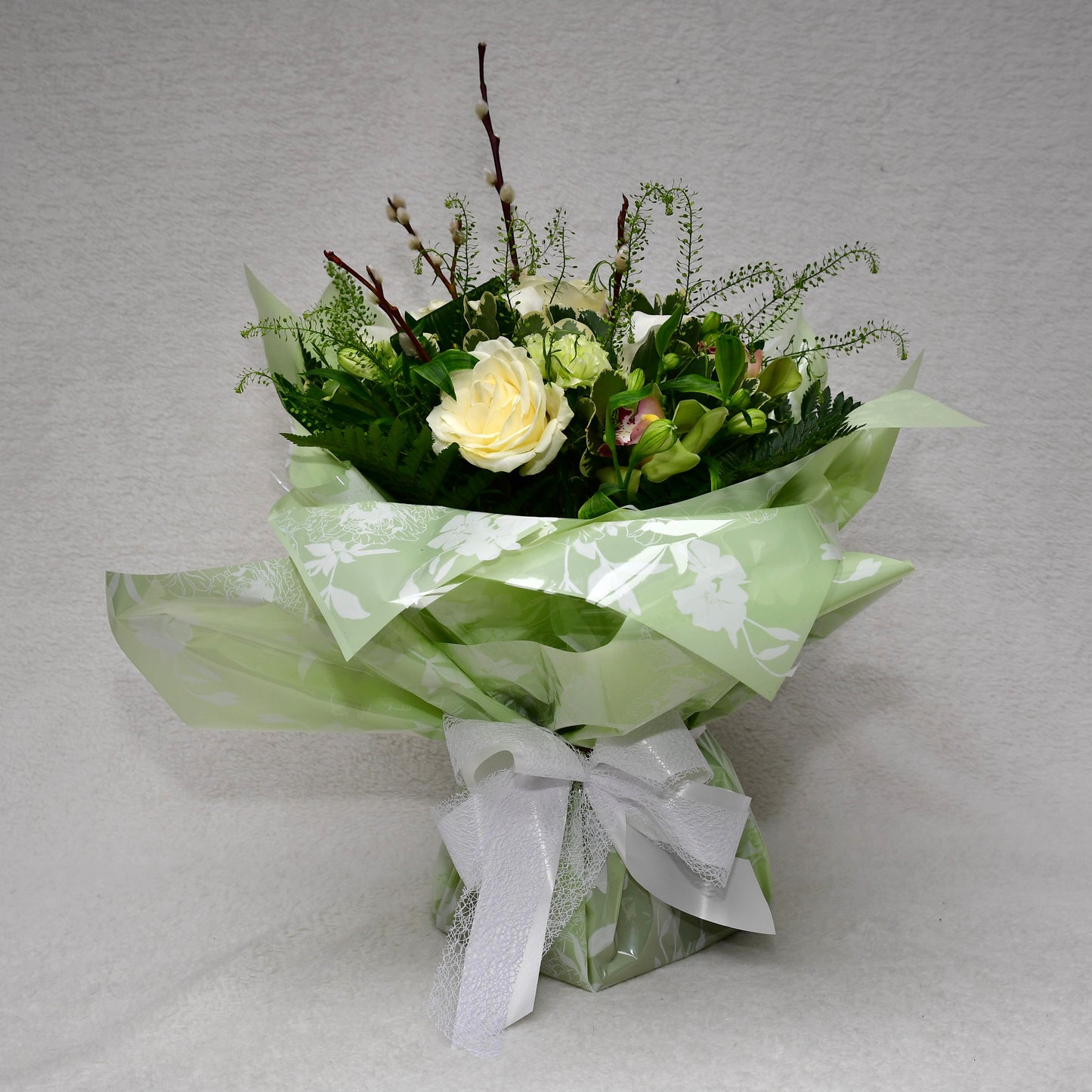 Hand-tied, gift wrapped bouquet including a selection of green and white flowers with complimentary foliage