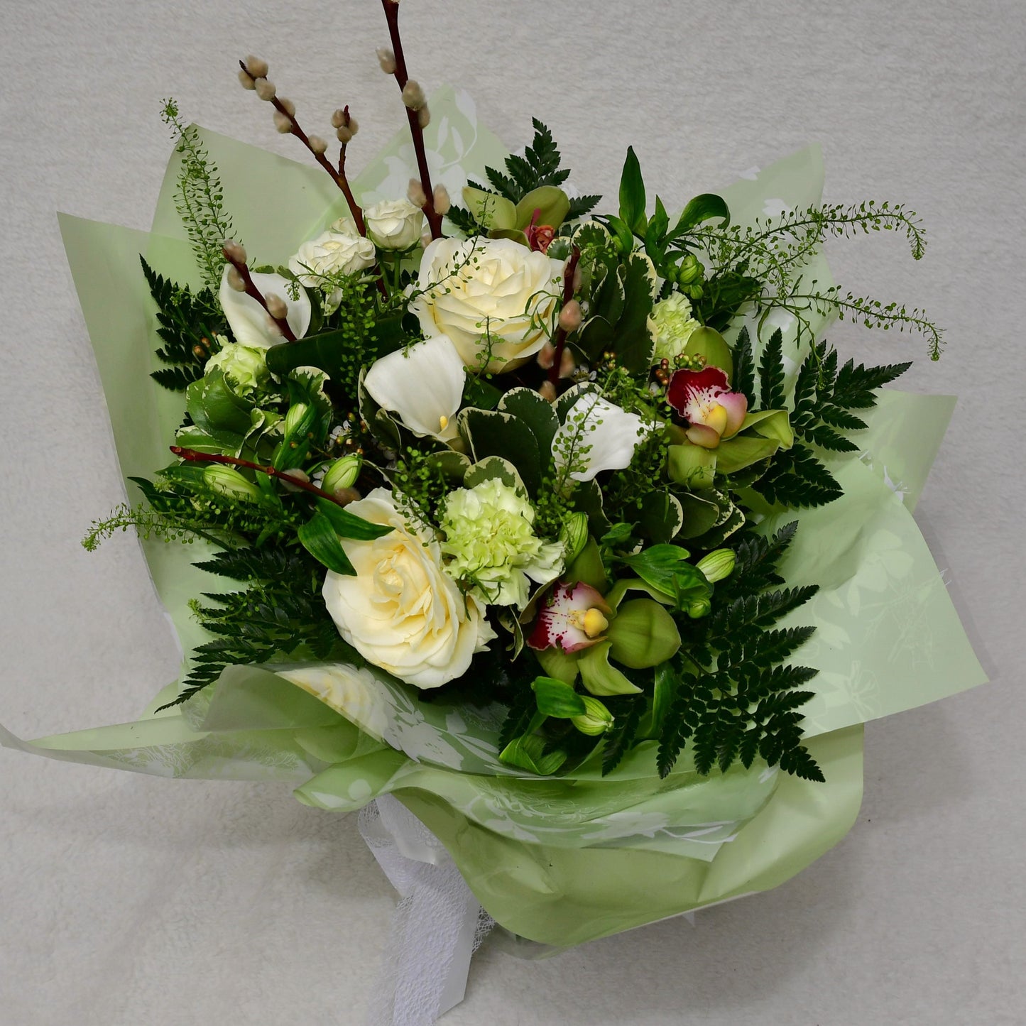 Hand-tied, gift wrapped bouquet including a selection of green and white flowers with complimentary foliage