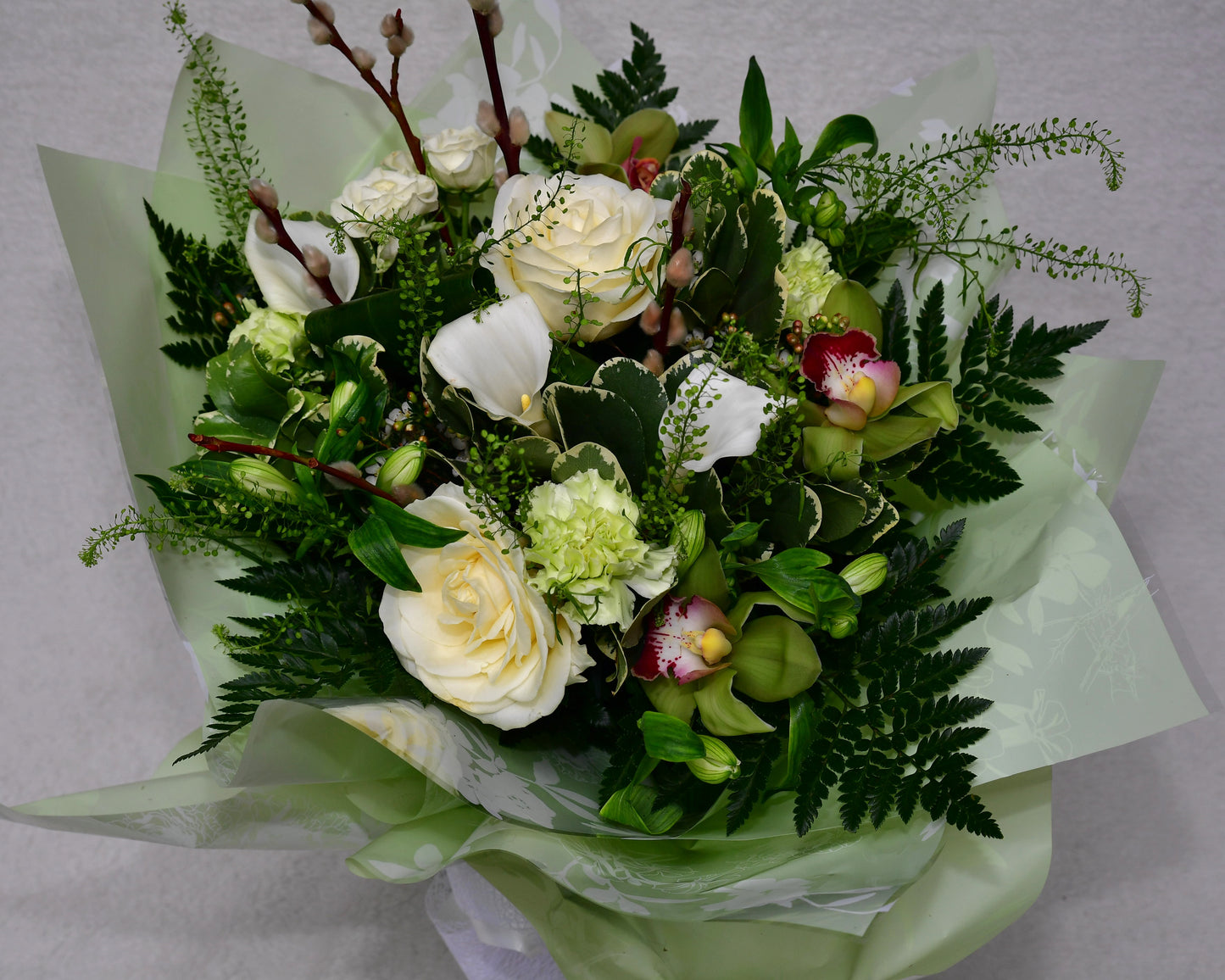 Hand-tied, gift wrapped bouquet including a selection of green and white flowers with complimentary foliage