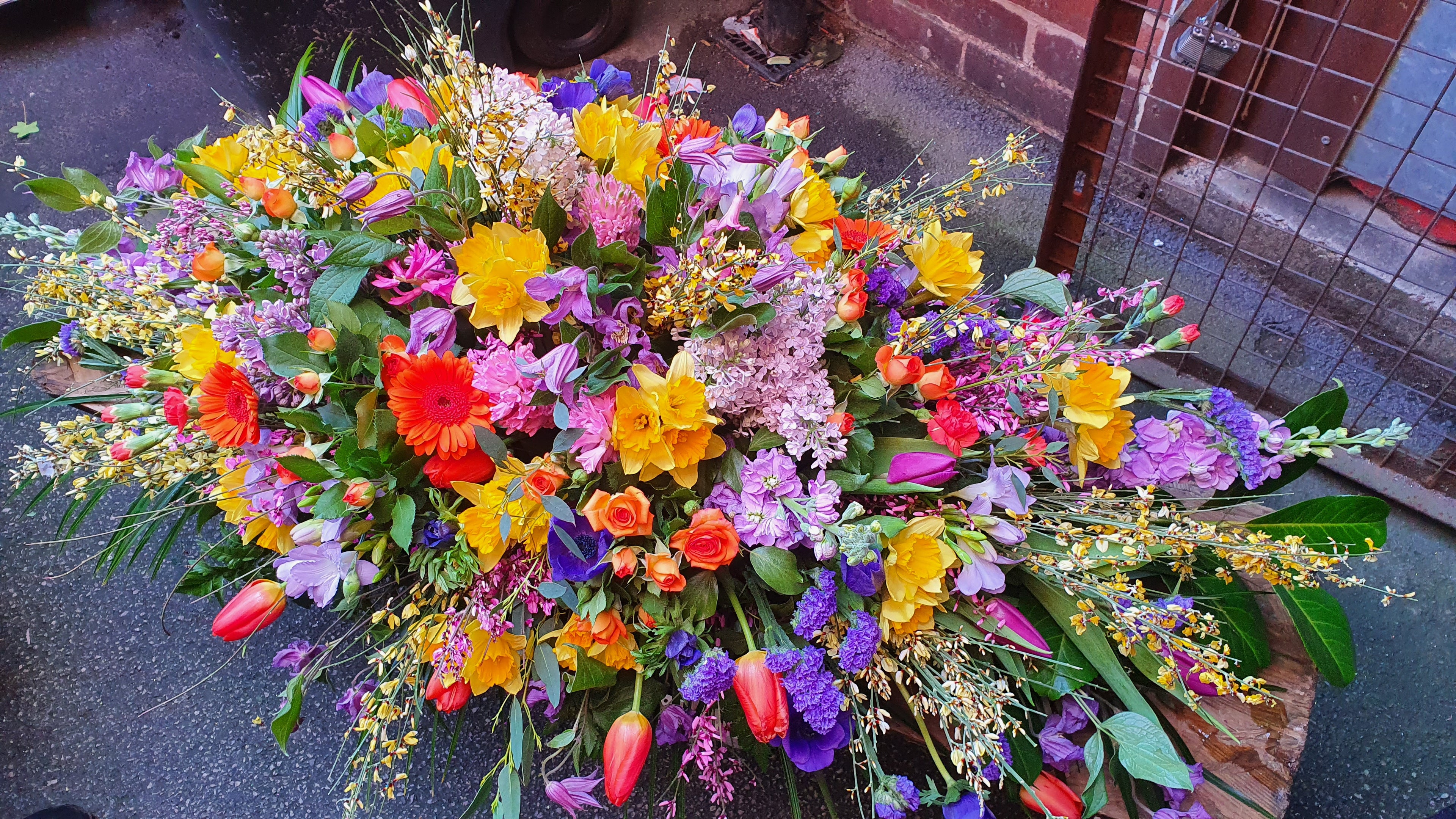 Bright floral casket spray of spring flowers