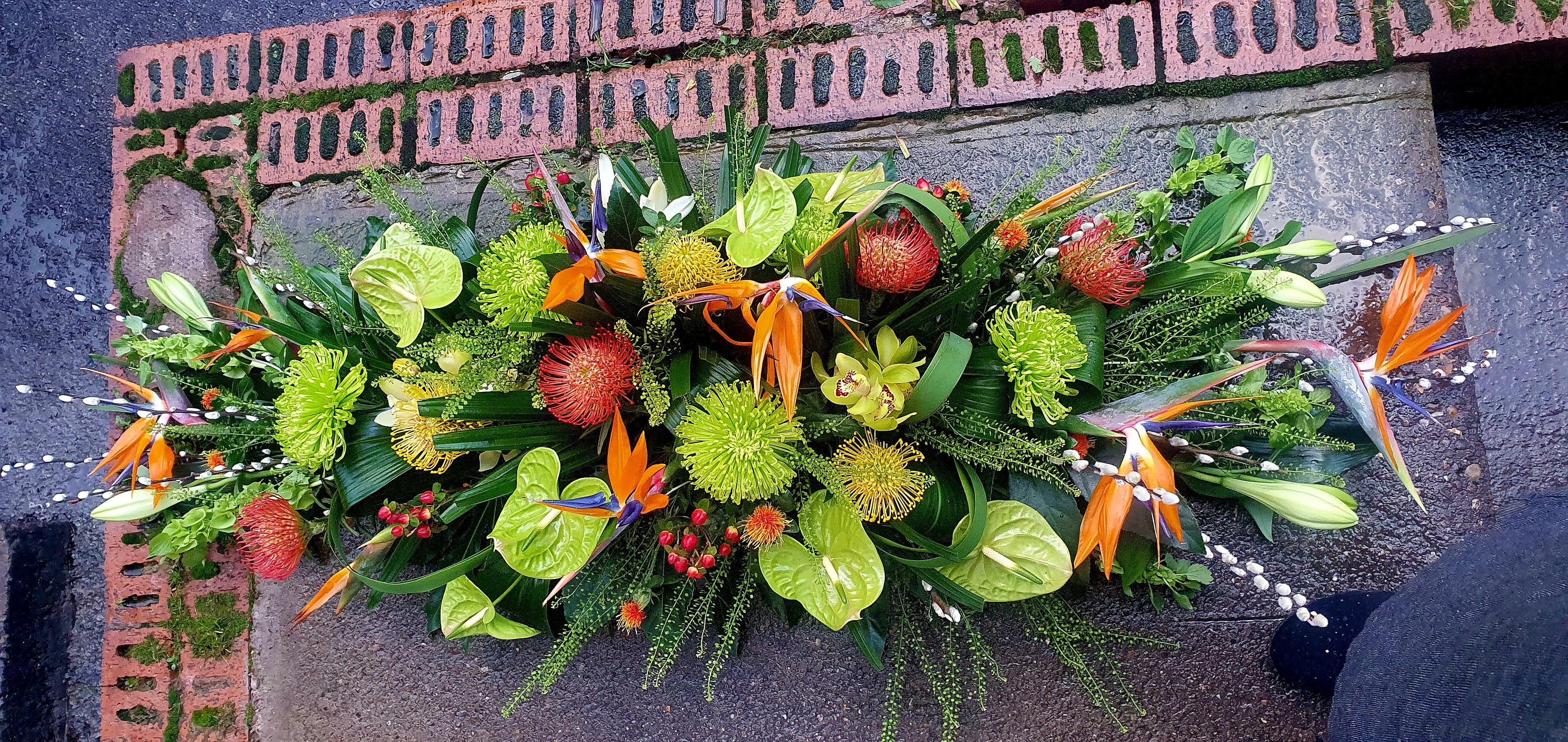 Tropical casket spray in greens,orange and red