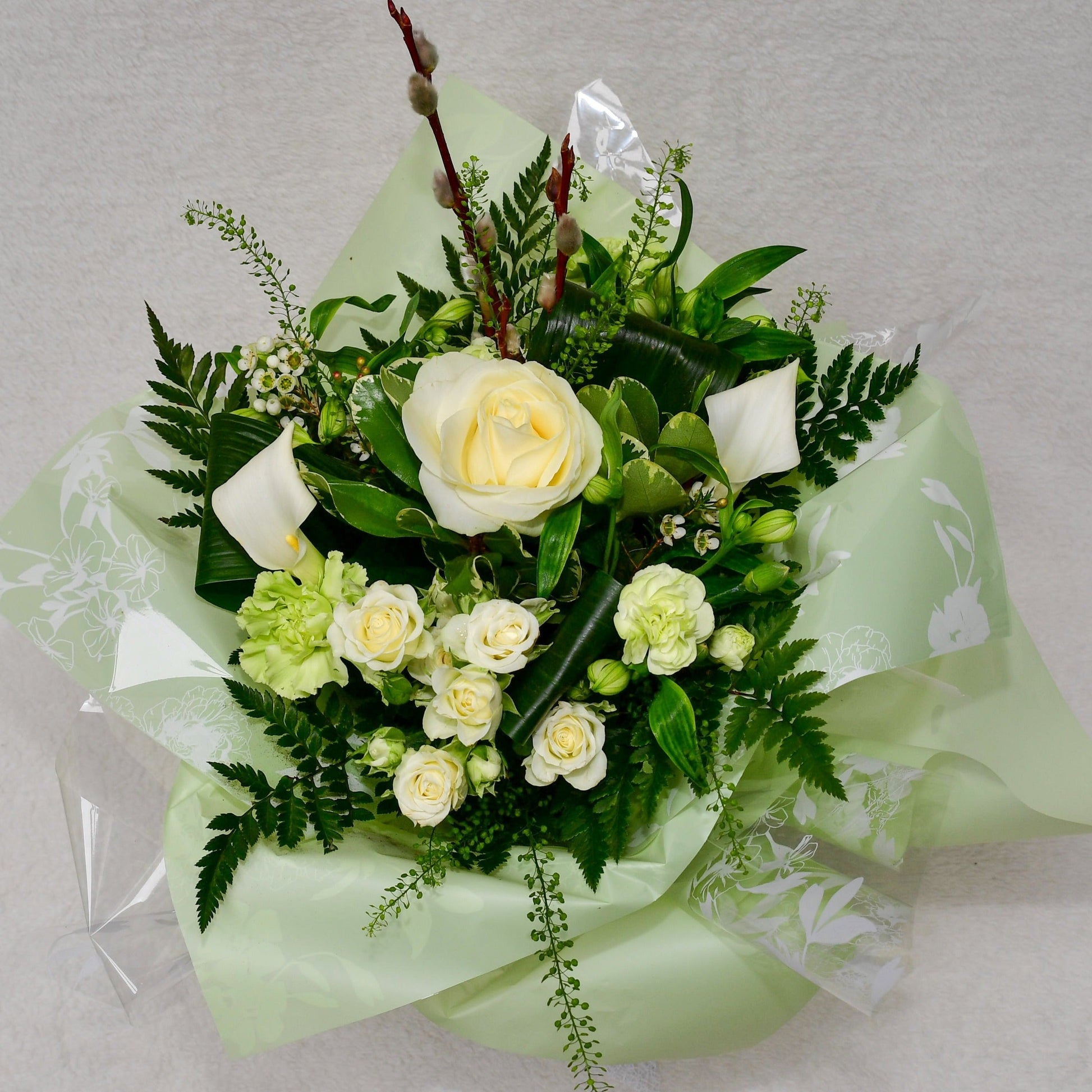 Hand-tied, gift wrapped bouquet including a selection of green and white flowers with complimentary foliage