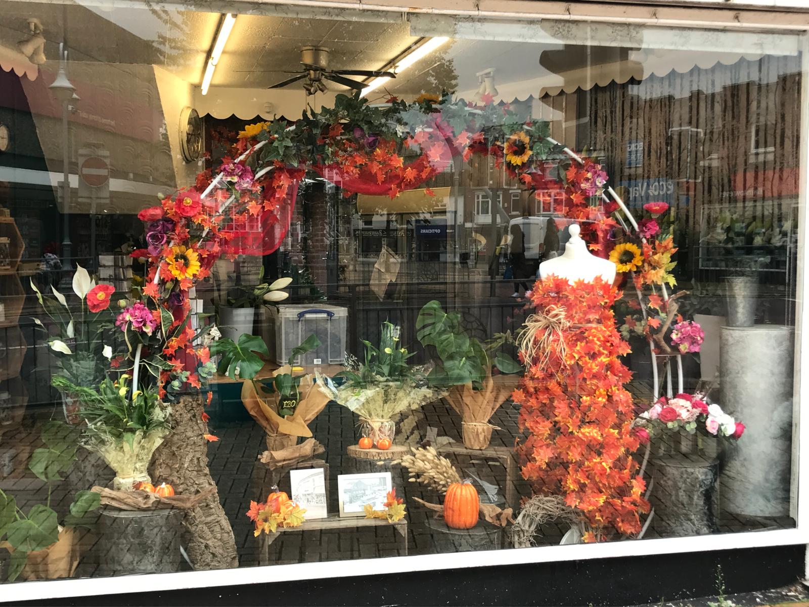 Shop window decorated for autumn with leaves and pumpkins