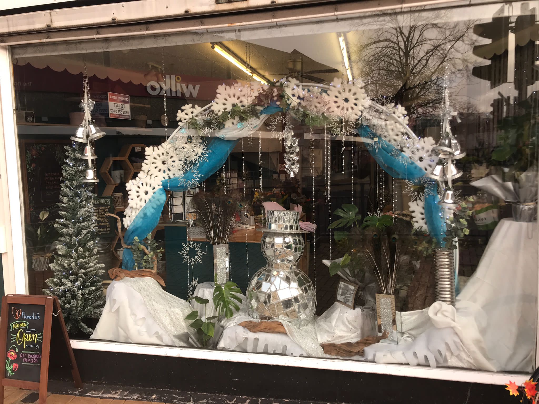 Award winning winter window display featuring a snowflake arch and discoball snowman